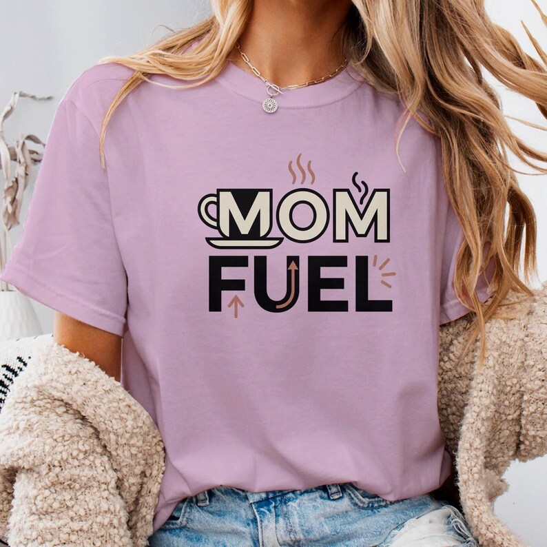 Mom Fuel retro coffee typography graphic t-shirt printed on Comfort Colors garment-dyed vintage washed heavyweight tee featuring coffee cup M letterform with steam lines and energy arrows in terracotta black and cream