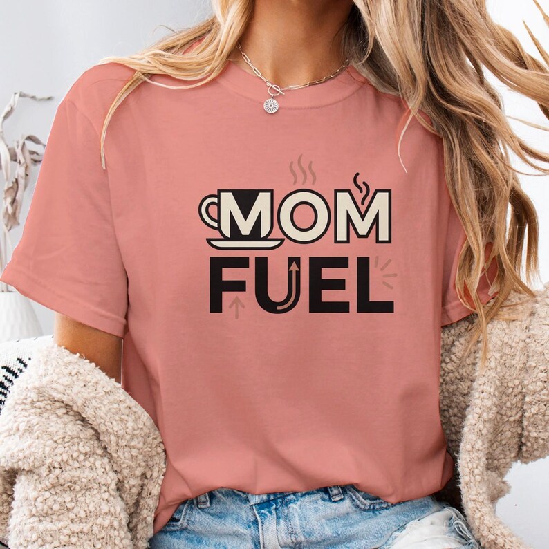 Mom Fuel retro coffee typography graphic t-shirt printed on Comfort Colors garment-dyed vintage washed heavyweight tee featuring coffee cup M letterform with steam lines and energy arrows in terracotta black and cream