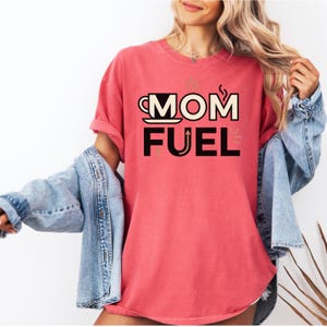 Mom Fuel retro coffee typography graphic t-shirt printed on Comfort Colors garment-dyed vintage washed heavyweight tee featuring coffee cup M letterform with steam lines and energy arrows in terracotta black and cream