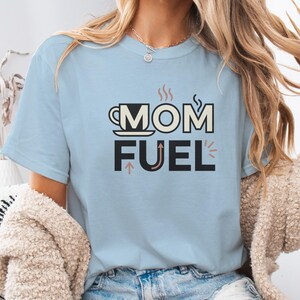 Mom Fuel retro coffee typography graphic t-shirt printed on Comfort Colors garment-dyed vintage washed heavyweight tee featuring coffee cup M letterform with steam lines and energy arrows in terracotta black and cream