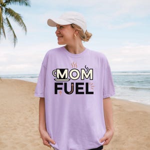 Mom Fuel retro coffee typography graphic t-shirt printed on Comfort Colors garment-dyed vintage washed heavyweight tee featuring coffee cup M letterform with steam lines and energy arrows in terracotta black and cream