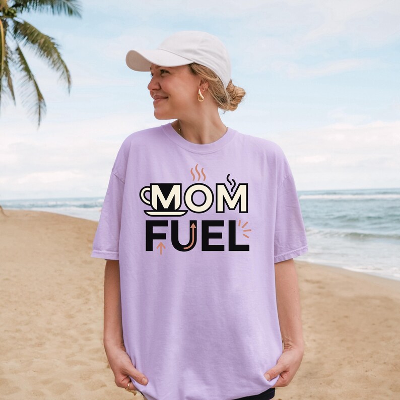 Mom Fuel retro coffee typography graphic t-shirt printed on Comfort Colors garment-dyed vintage washed heavyweight tee featuring coffee cup M letterform with steam lines and energy arrows in terracotta black and cream