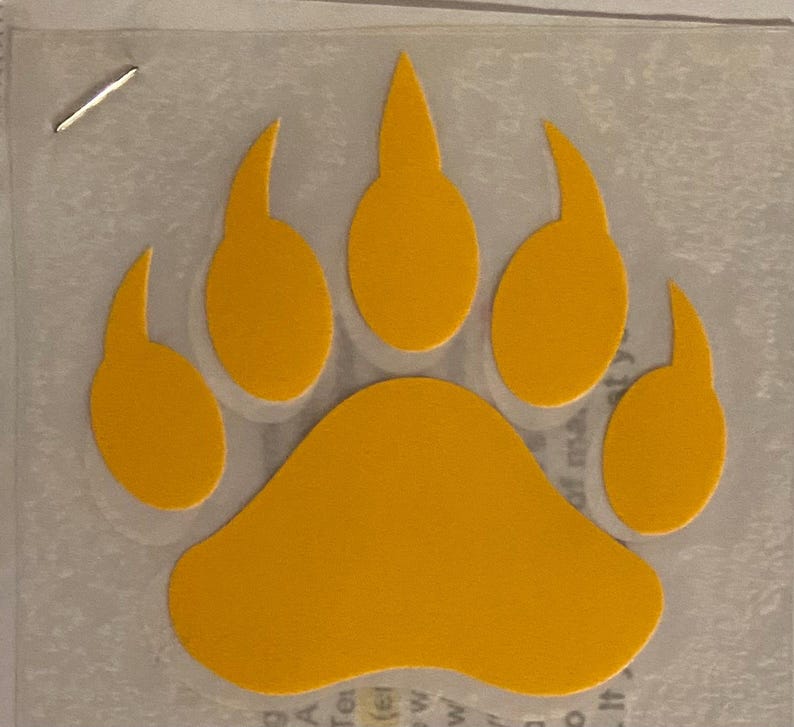 May include: A yellow bear paw print decal. The paw print is outlined in black and has five toes.