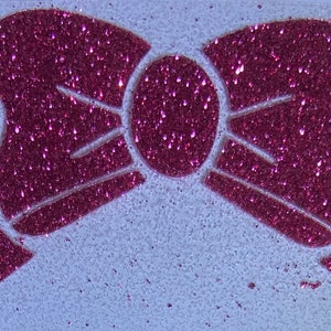 May include: A pink glitter bow with a white background.