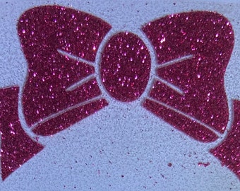 May include: A pink glitter bow with a white background.