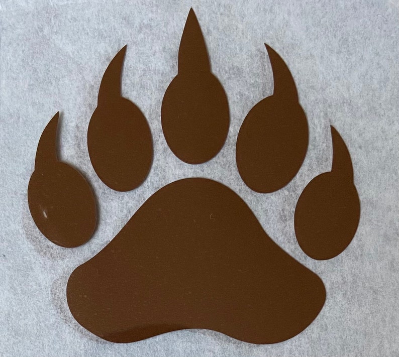 May include: A brown bear paw print decal. The paw print is a silhouette of a bear's paw with five toes.