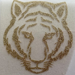 May include: Gold glitter tiger head silhouette on a white background.
