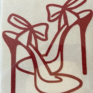 May include: Two red glitter high heel shoes with bows. The shoes are outlined in a darker red and have a pointed toe.