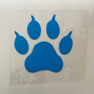 May include: A blue paw print sticker. The paw print is a solid, vibrant blue color and is centered on a clear, square background. The sticker is likely for a pet or animal lover.