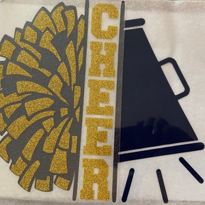 May include: Gold glitter CHEER letters with a black and gold glitter pom pom and a black megaphone with gold glitter accents.