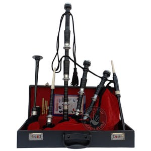 Puede incluir: Un juego de gaita negra expuesto en un estuche negro abierto con interior de terciopelo rojo. Las gaitas tienen detalles plateados y cuerdas negras. El estuche tiene un cierre de combinación.