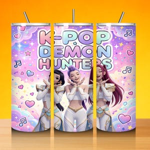 May include: A K-Pop Demon Hunters tumbler featuring three anime-style characters in white outfits. The tumbler has a purple and pink background with musical notes, hearts, and stars. The text "K-Pop Demon Hunters" is displayed prominently.