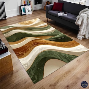 May include: A rectangular rug with an abstract, flowing design. It features undulating bands of green, brown, beige, and white, with gold accents. The rug is placed on a wooden floor. The rug's design evokes a sense of movement.