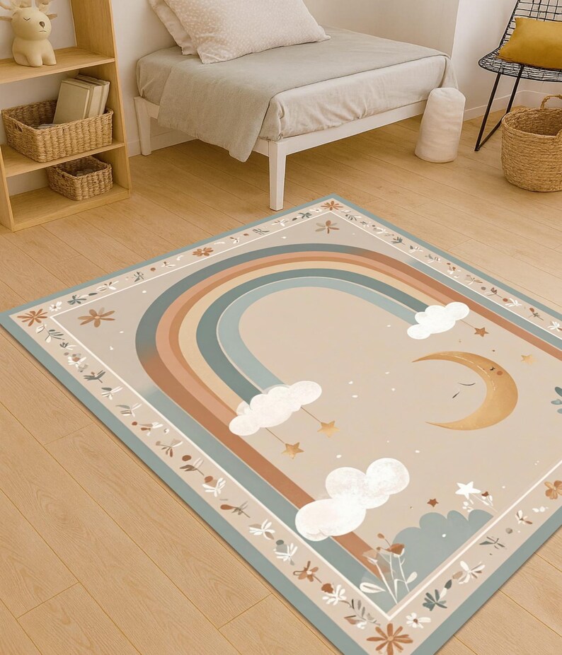 Puede incluir: Una alfombra rectangular con un dise&ntilde;o de arco&iacute;ris en colores apagados beige, marr&oacute;n y azul. La alfombra presenta una luna creciente, nubes y estrellas. El borde tiene un patr&oacute;n floral. Esta alfombra es adecuada para una habitaci&oacute;n infantil.
