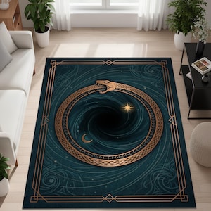 May include: A rectangular rug with a teal background and a gold border. The rug features a gold ouroboros design encircling a black vortex, with a star and crescent moon. The rug is placed on a light wood floor.