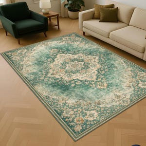 K&ouml;nnte beinhalten: Ein rechteckiger Teppich im Used-Look mit einem zentralen floralen Medaillon-Design. Der Teppich hat eine Farbpalette aus T&uuml;rkis und Creme mit Akzenten in Pfirsich und Beige. Er liegt auf einem hellen Holzboden, umgeben von M&ouml;beln.