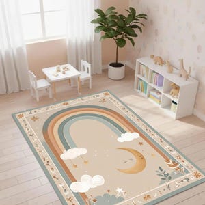 Puede incluir: Alfombra rectangular con un dise&ntilde;o de arco&iacute;ris en tonos beige, azul y marr&oacute;n. La alfombra presenta una luna creciente, nubes y estrellas, con un borde floral. La alfombra est&aacute; colocada en una habitaci&oacute;n infantil.