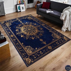 Könnte beinhalten: Ein rechteckiger marineblauer Teppich mit einem verzierten goldenen Blumendesign. Der Teppich hat ein zentrales Medaillon und einen detaillierten Rand mit Blumen- und Scrollmustern. Der Teppich liegt auf einem Holzboden.