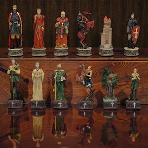 Pode incluir: Um conjunto de peças de xadrez com tema medieval. As peças incluem reis, rainhas, cavaleiros a cavalo e torres, com detalhes históricos. A paleta de cores inclui vermelho, verde e dourado, com cruzes nas bases.