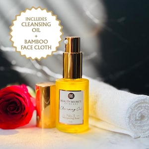 May include: A yellow glass bottle of Beauty Secret Skincare No. 3 Whispering Rose Cleansing Oil with a gold pump, a red rose, and a white rolled bamboo face cloth. A gold-rimmed label reads: INCLUDES CLEANSING OIL + BAMBOO FACE CLOTH.