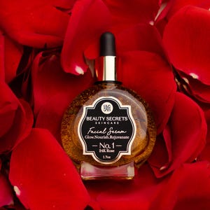 Puede incluir: Un frasco de vidrio redondo de suero facial Beauty Secrets Skincare con tapa de gotero negra. La etiqueta dice Beauty Secrets Skincare, Facial Serum, Glow.Nourish.Rejuvenate, No.1, 24K Rose, 1.7oz. El suero interior es de tono dorado y transl&uacute;cido.