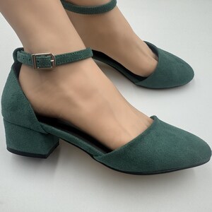 Op de afbeelding: Groene su&egrave;de enkellaarsjes met een lage blokhak. De schoenen hebben een puntige neus en een gespsluiting op de enkelband. De hakken zijn ongeveer 5 cm hoog.