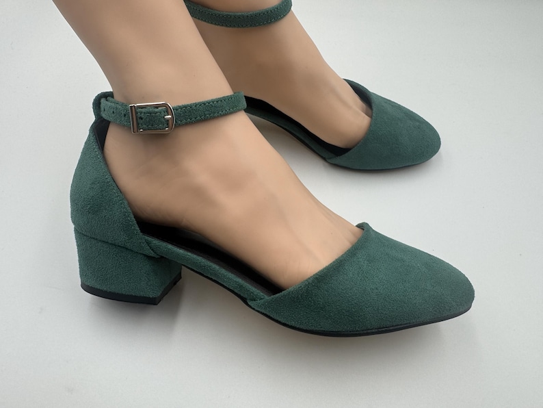 Op de afbeelding: Groene su&egrave;de enkellaarsjes met een lage blokhak. De schoenen hebben een puntige neus en een gespsluiting op de enkelband. De hakken zijn ongeveer 5 cm hoog.