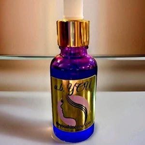 Peut inclure: Une bouteille en verre violet avec un bouchon dor&eacute; et un applicateur blanc. La bouteille porte une &eacute;tiquette dor&eacute;e avec le texte "u.b. YOU" et une silhouette de visage de femme. L'adresse du site Web byouskincare.com figure &eacute;galement sur l'&eacute;tiquette. La bouteille est remplie d'un liquide clair.