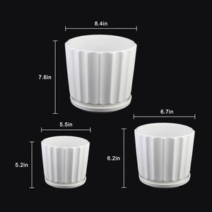 May include: Three white ceramic plant pots with a ribbed design and attached saucers. The largest pot is 8.4 inches wide and 7.6 inches tall. The medium pot is 6.7 inches wide and 6.2 inches tall. The smallest pot is 5.5 inches wide and 5.2 inches tall.