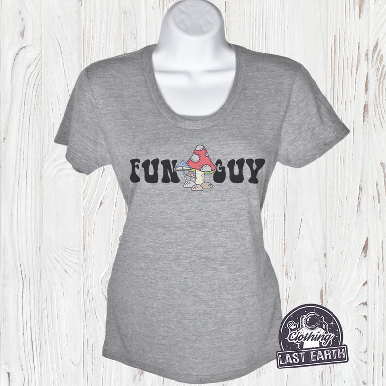 K&ouml;nnte beinhalten: Ein hellgraues T-Shirt mit einem Aufdruck von Pilzen und dem Text "FUN GUY" in einer Retro-Schrift.