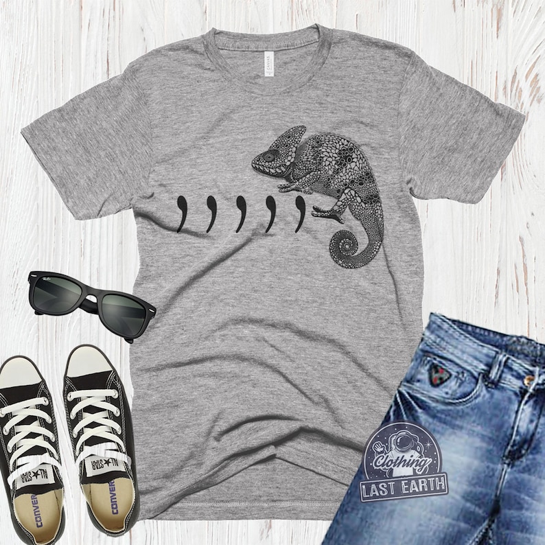 Peut inclure: T-shirt gris avec une illustration de cam&eacute;l&eacute;on noir et blanc et le texte ",,,,," imprim&eacute; sur le devant.