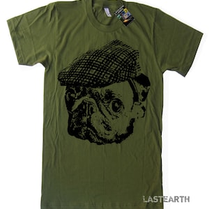 Pode incluir: Uma camiseta verde com um gr&aacute;fico preto e branco de um pug usando um bon&eacute; plano. O texto "LASTEARTH" est&aacute; impresso no canto inferior direito da camiseta.