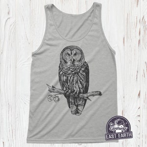 May include: A gray tank top with a black and white illustration of an owl perched on a branch. The owl has large, round eyes and a detailed feather pattern. The branch has a few leaves on it.