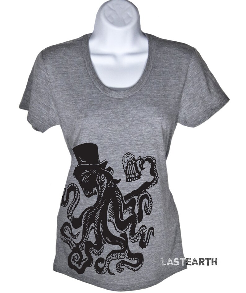 May include: A gray t-shirt with a black and white illustration of an octopus wearing a top hat and holding a beer mug. The octopus has eight tentacles and is in a relaxed pose. The text "LASTEARTH" is printed on the bottom right corner of the shirt.