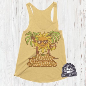 May include: A yellow tank top featuring a graphic of a smiling sun wearing sunglasses and holding a coconut drink. The sun is surrounded by palm trees and the text "Hello Summer" is printed below. The tank top has a racerback style and a curved hem.