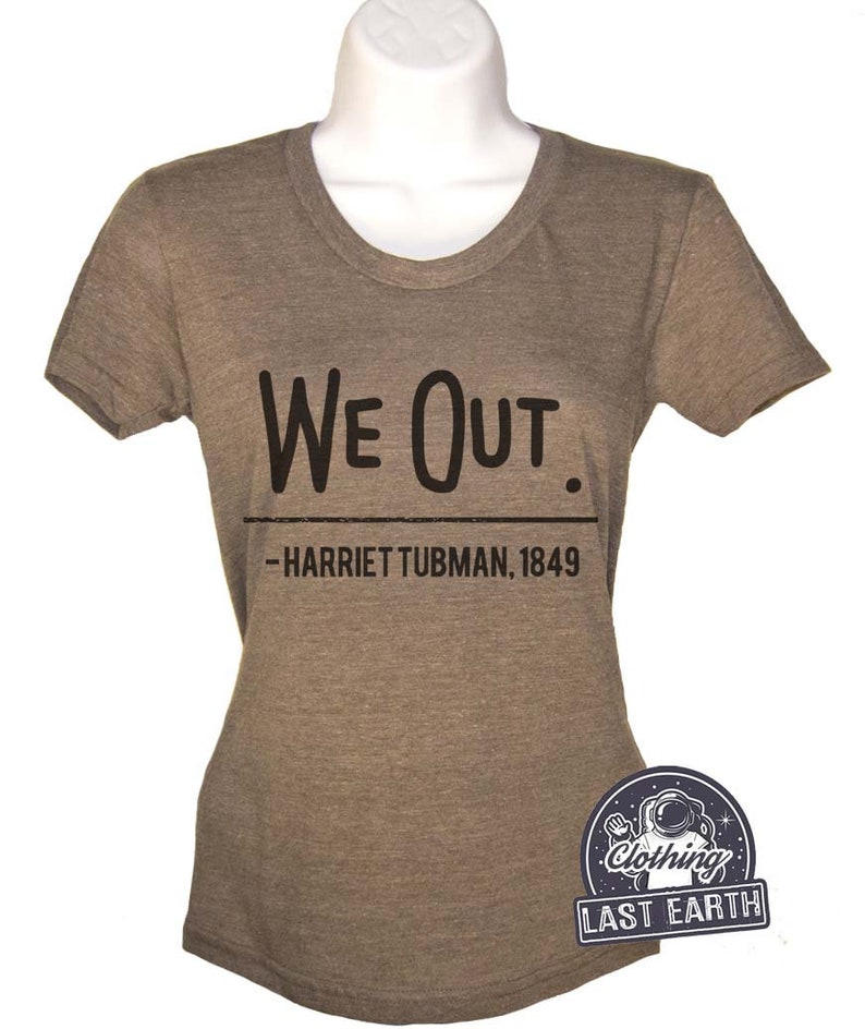 Puede incluir: Una camiseta marr&oacute;n con el texto "We Out." y la cita "Harriet Tubman, 1849" impresa en ella. La camiseta est&aacute; hecha por Last Earth Clothing.