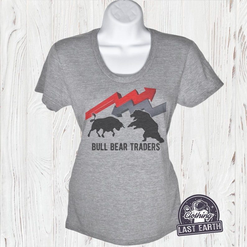 Puede incluir: Camiseta gris con un gr&aacute;fico de un toro y un oso enfrentados con flechas rojas y grises. El texto "BULL BEAR TRADERS" est&aacute; impreso debajo del gr&aacute;fico.
