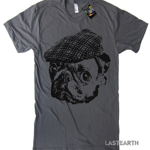 Pode incluir: Uma camiseta cinza escura com um gr&aacute;fico preto e branco de um pug usando um bon&eacute; plano. O texto "LASTEARTH" est&aacute; impresso no canto inferior direito da camiseta.