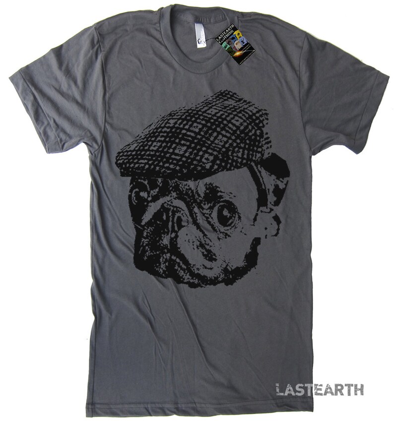 Pode incluir: Uma camiseta cinza escura com um gr&aacute;fico preto e branco de um pug usando um bon&eacute; plano. O texto "LASTEARTH" est&aacute; impresso no canto inferior direito da camiseta.