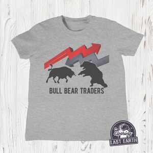 Puede incluir: Camiseta gris con un gr&aacute;fico de toro y oso negros, flechas rojas y grises, y el texto "BULL BEAR TRADERS".