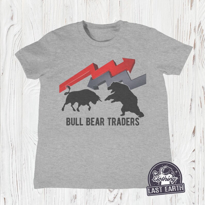 Puede incluir: Camiseta gris con un gr&aacute;fico de toro y oso negros, flechas rojas y grises, y el texto "BULL BEAR TRADERS".