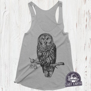 May include: Gray tank top with a black and white illustration of an owl perched on a branch. The owl is looking directly at the viewer. The text "Clothing Last Earth" is printed on the bottom right corner of the tank top.