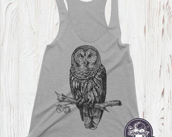 May include: Grey tank top featuring a black and white illustration of an owl perched on a branch. The owl is looking directly at the viewer. The text "Clothing Last Earth" is printed on the bottom right corner of the tank top.