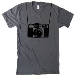 May include: A dark gray t-shirt with a black and white illustration of a vintage camera with a strap.