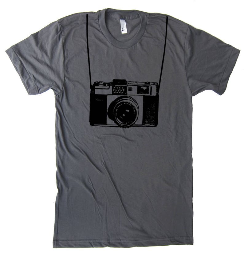 May include: A dark gray t-shirt with a black and white illustration of a vintage camera with a strap.