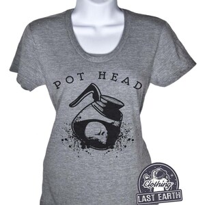 Puede incluir: Camiseta gris con un gr&aacute;fico en blanco y negro de una cafetera con una calavera en su interior. El texto "POT HEAD" est&aacute; por encima del gr&aacute;fico. La camiseta es de Last Earth Clothing.