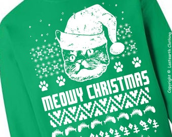 Peut inclure: Sweat-shirt vert avec un motif blanc représentant un chat portant un bonnet de Père Noël. Le texte "MEOWY CHRISTMAS" est imprimé en dessous, avec des flocons de neige, des empreintes de pattes et d'autres motifs festifs. Article de fête.