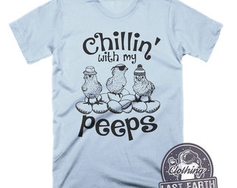 May include: Light blue t-shirt with a black graphic of three cartoon chicks wearing hats and sunglasses. The text "Chillin' with my peeps" is printed below the chicks.