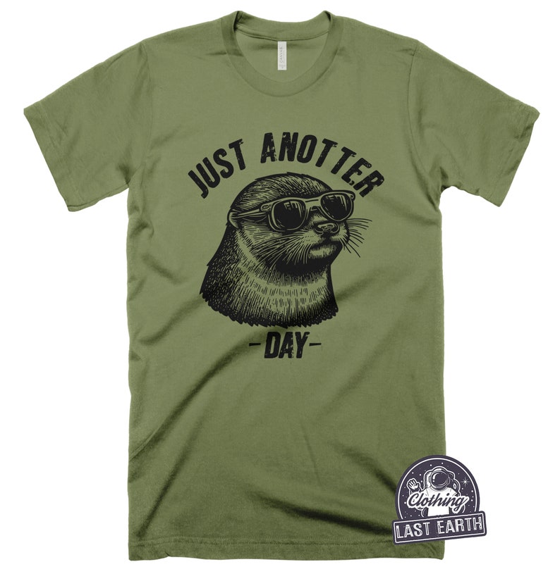 May include: A green t-shirt with a black graphic of an otter wearing sunglasses and the text "Just Anotter Day".