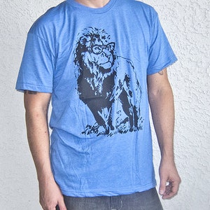 May include: A blue t-shirt with a black and white graphic of a lion wearing glasses. The lion is facing to the right and has a mane.